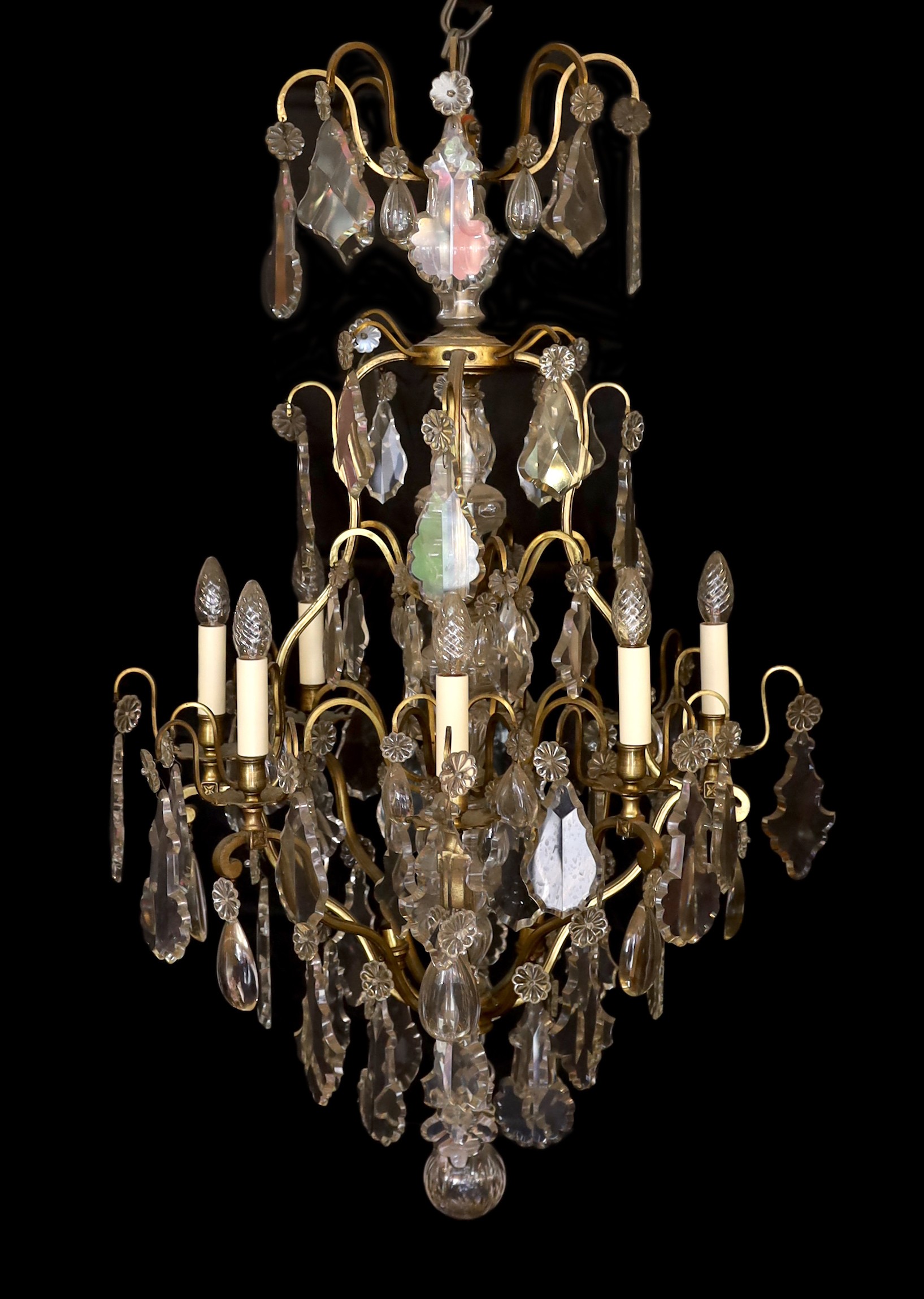 An early 20th century French bronze and cut glass twelve light chandelier, hung with tear, lozenge and flowerhead shaped drops, drop 114cm. width 72cm